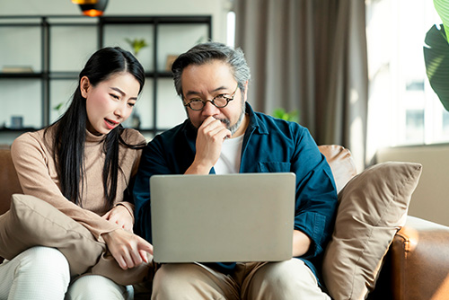 Student loan co-applicant Parent co-applicant for student loan. Daughter and father looking at a laptop screen, focused on student loan application.
